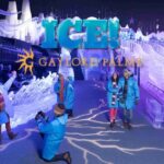 Visitors wearing blue parkas posing in front of a giant ice sculpture train with "ICE! Gaylord Palms" branding overlay.
