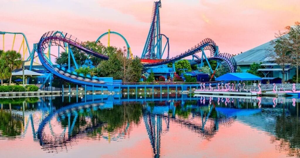 Scenic sunset view of SeaWorld roller coaster tracks reflected clearly on the calm water surface.