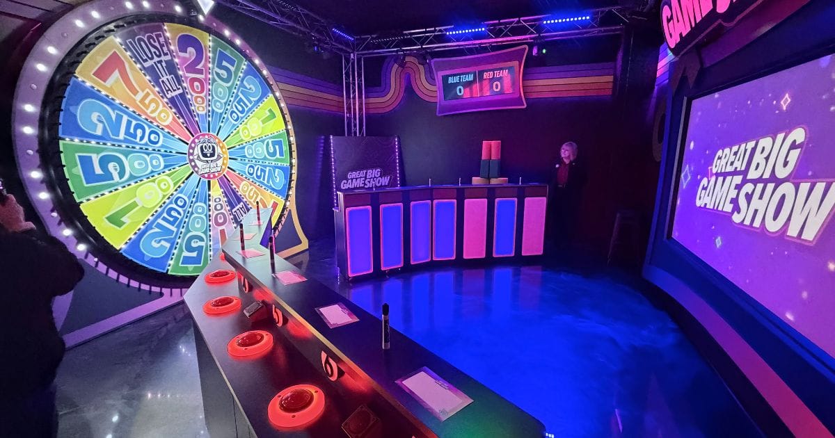 Interior set of the Great Big Game Show featuring team podiums and screens