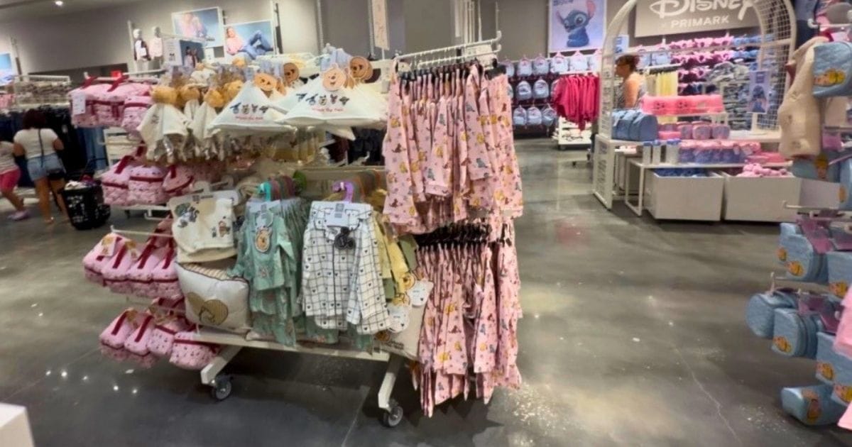 Inside the New Primark at Orlando Vineland Premium Outlets: Discount Disney Merchandise Guide 5 Winnie the Pooh and classic Disney baby clothing sets hanging on a store rack at Primark.