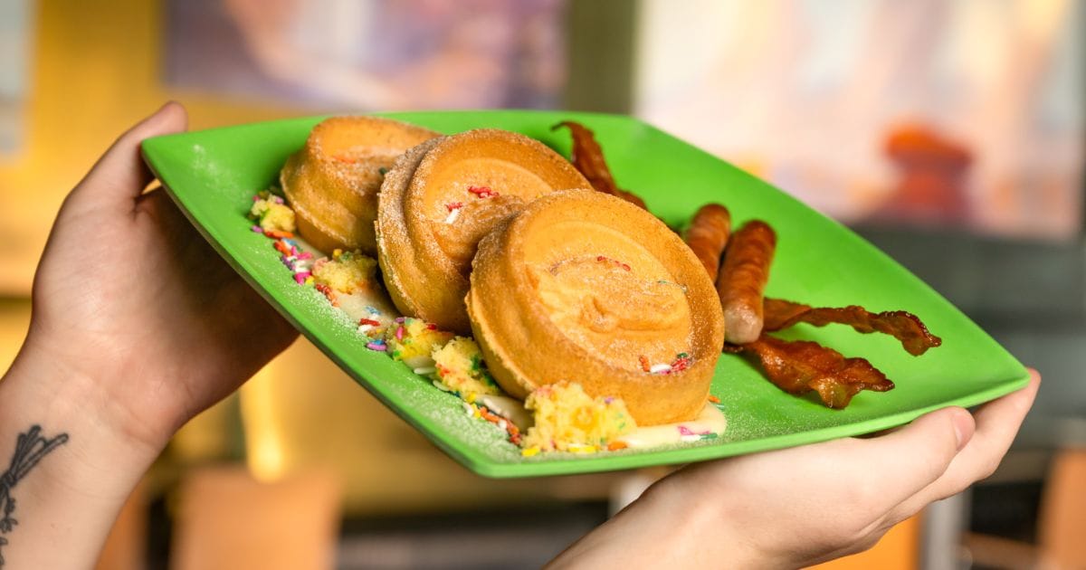 Sweet breakfast platter featuring character-embossed birthday cake waffles, funfetti crumbles, savory bacon, and breakfast link sausages