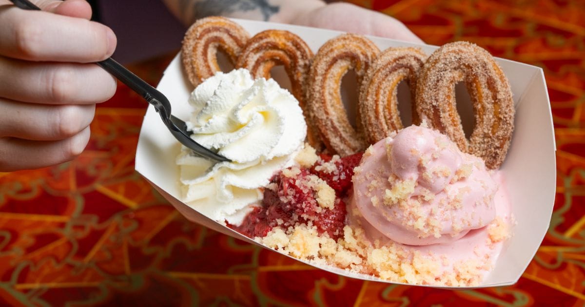 Decadent theme park sundae featuring looped cinnamon-sugar churros, strawberry soft serve, sweet berry reduction, and shortcake crumble