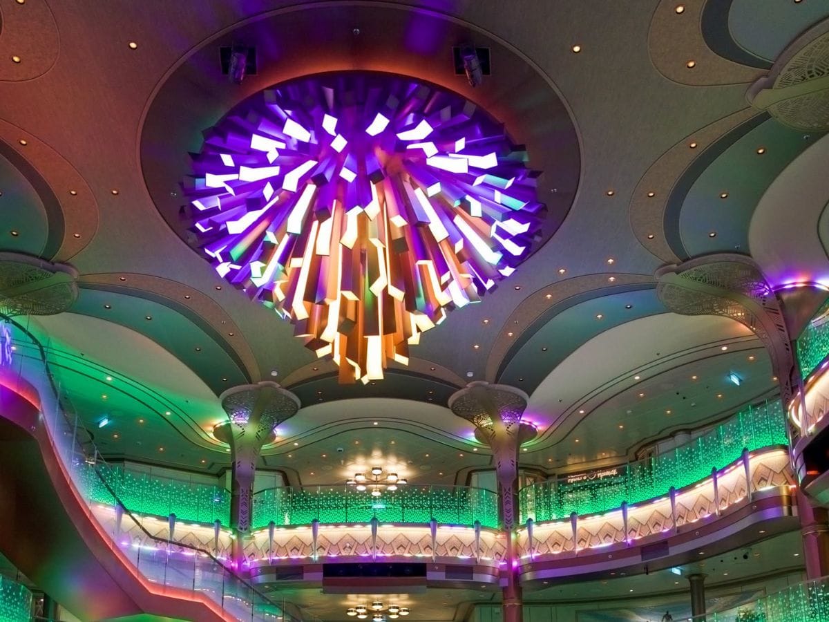 Vibrant purple and gold modern light fixture in the Disney Destiny atrium during Halloween on the High Seas
