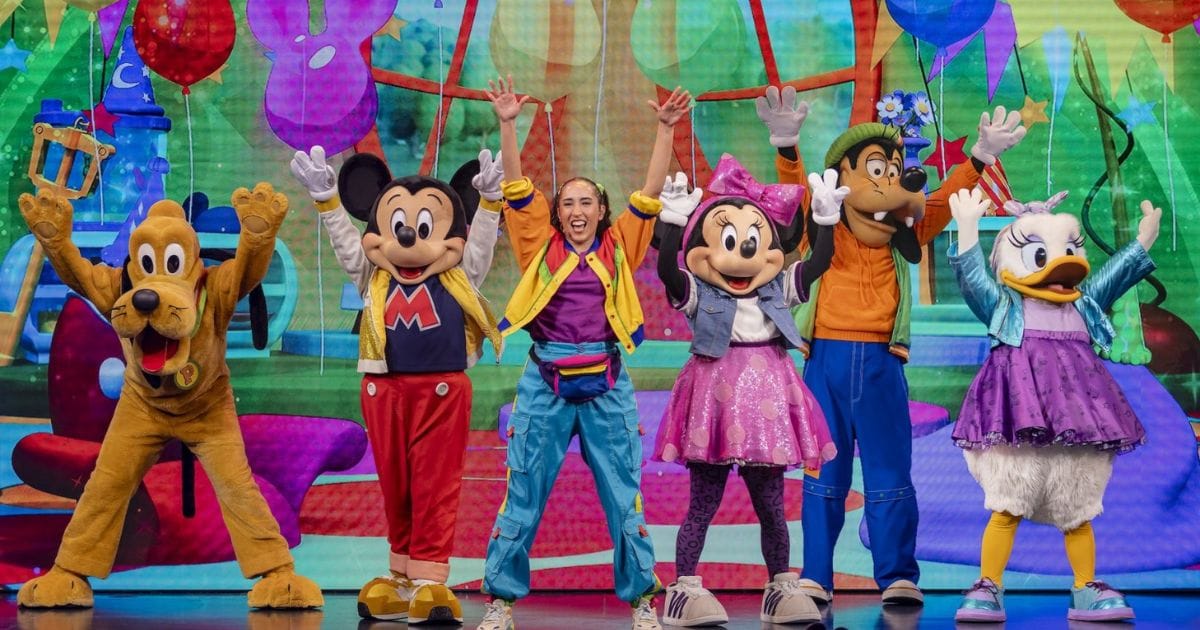 Live host and Disney characters Mickey, Minnie, Goofy, Daisy, and Pluto cheering on stage during Disney Jr. Mickey Mouse Clubhouse Live