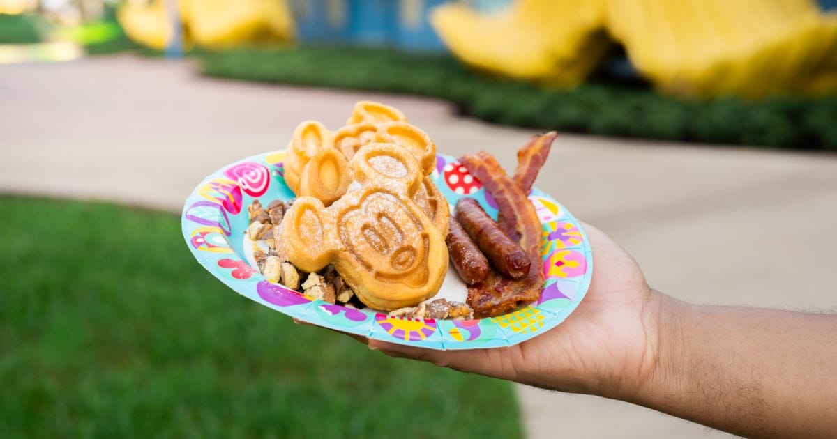 Disney breakfast platter featuring golden Mickey waffles, side servings of bacon and sausage, and sweet banana caramel toppings