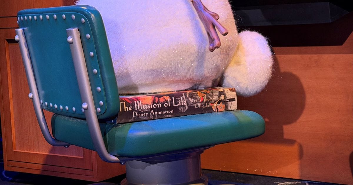 Audio-Animatronic Olaf sitting on a copy of Frank Thomas and Ollie Johnston's The Illusion of Life book used as a booster seat