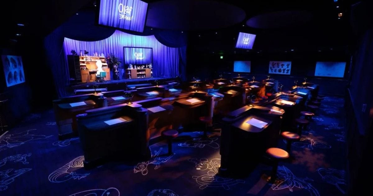 Wide interior view of the Olaf Draws animation academy showing tiers of wooden animator desks and stage screens