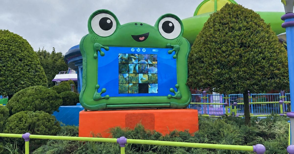 Set inside a green frog casing, the Lilypad digital screen displays a modular grid puzzle designed for interactive play inside Toy Story Land at Disney's Hollywood Studios