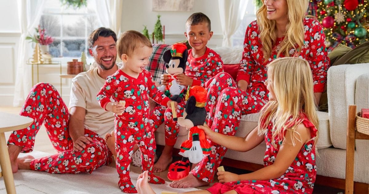Family sitting together in a living room wearing matching red Santa Mickey and Minnie Mouse holiday sleepwear.