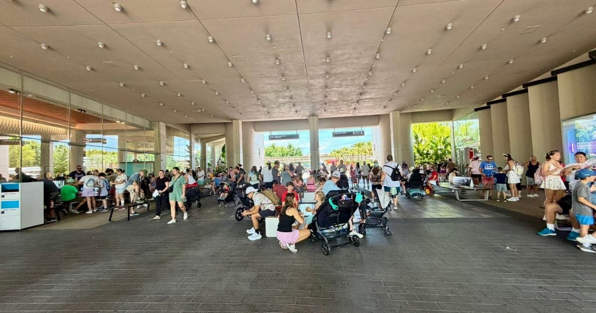 EPCOT Pin Trading Controversy: Breezeway Relocation and Rule Updates 3 Congested walkway at EPCOT with guests seated on the floor with pin trading displays