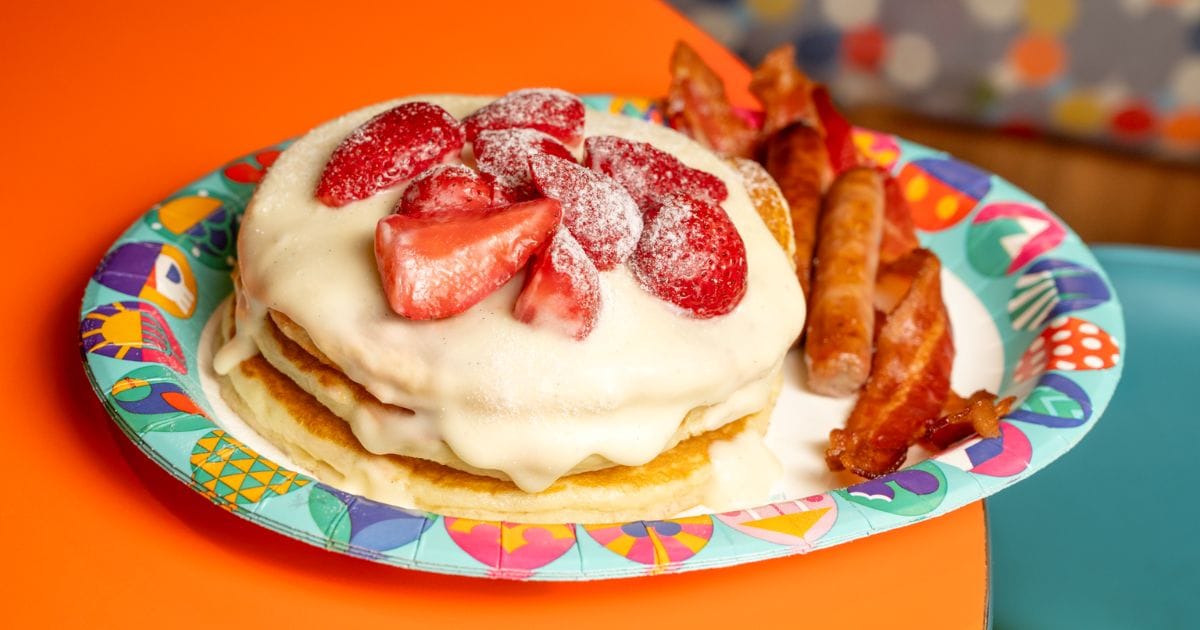 Sweet resort breakfast stack loaded with decadent vanilla cream custard, powdered sugar, ripe glazed strawberries, bacon, and breakfast sausage