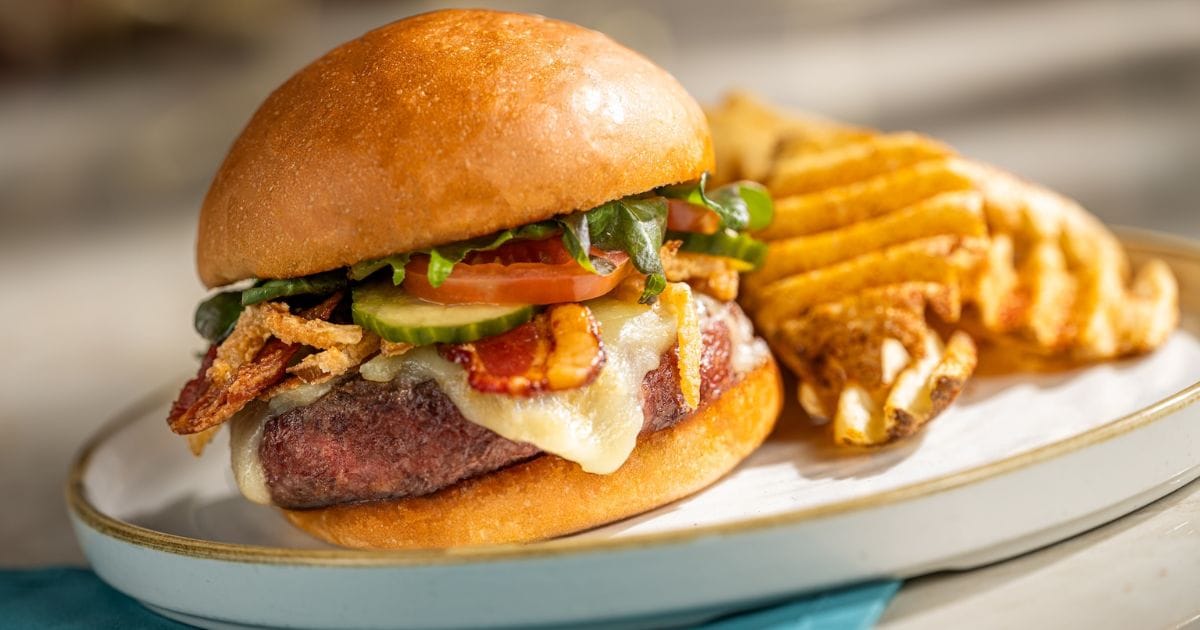 The Turf Club Burger with bacon, cheddar, and onion straws served with waffle fries