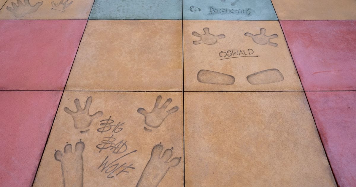 Colorful courtyard pavement tiles with handprints and signatures of Oswald the Lucky Rabbit, Big Bad Wolf, and Pocahontas