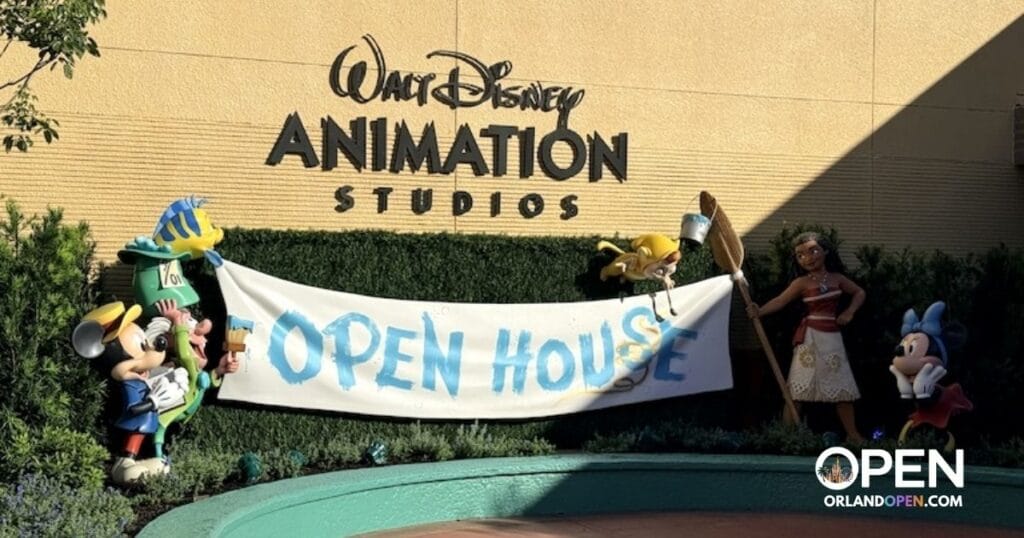 First look photo op at Disney’s Hollywood Studios featuring Moana, Mad Hatter, and Minnie Mouse holding an Open House banner beneath the Walt Disney Animation Studios sign.