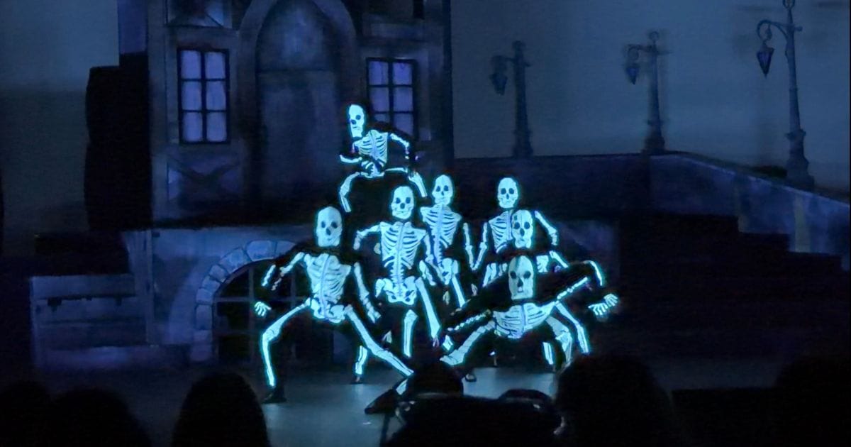Performers in glowing skeleton costumes dancing on stage during the Monster Stomp show at Howl-O-Scream Orlando