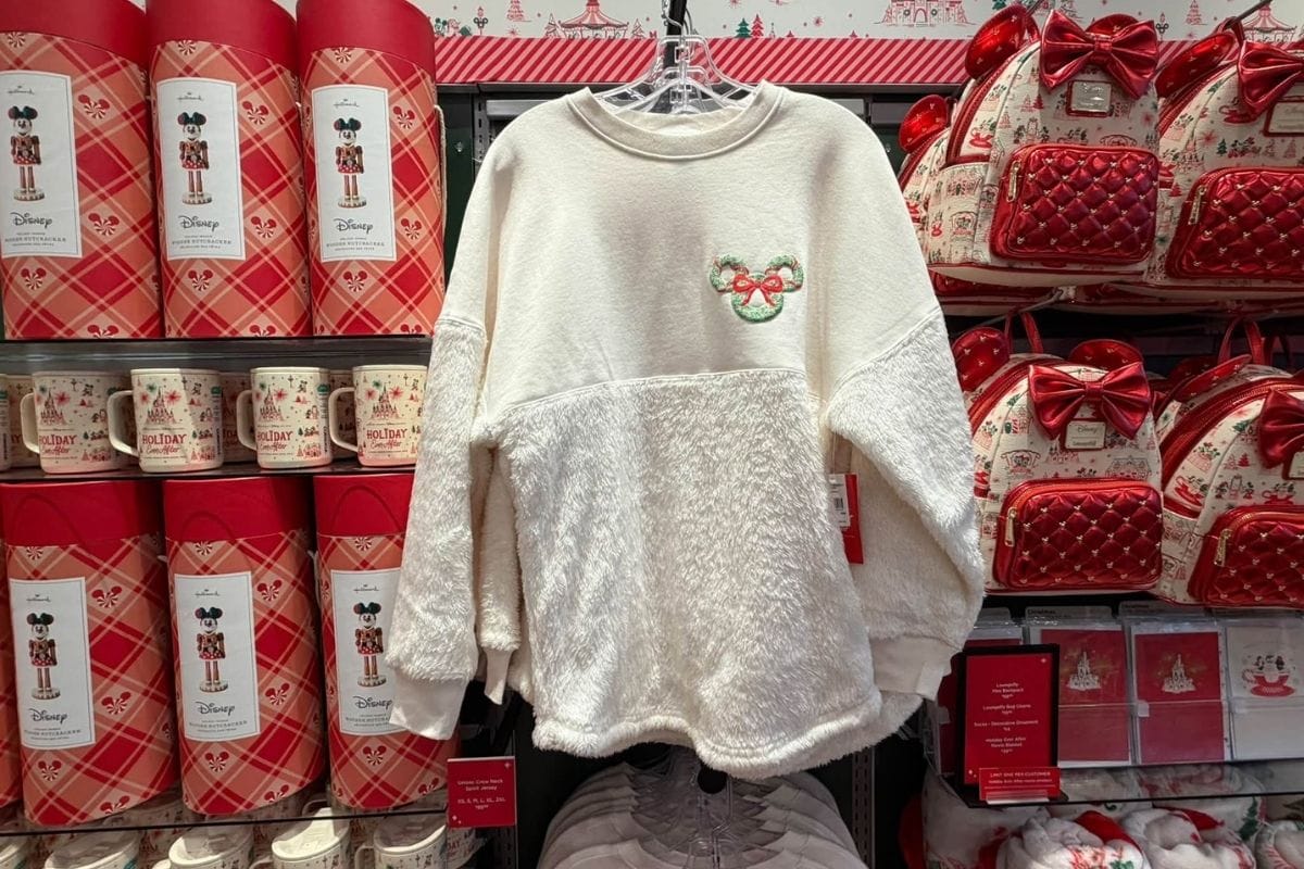 Hallmark and Disney Holiday Ever After Ivory Spirit Jersey displayed on a hanger at Disney Springs