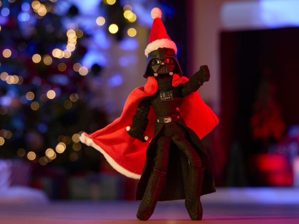 The Star Wars Darth on a Hearth plush figure sitting on a mantlepiece next to festive decor