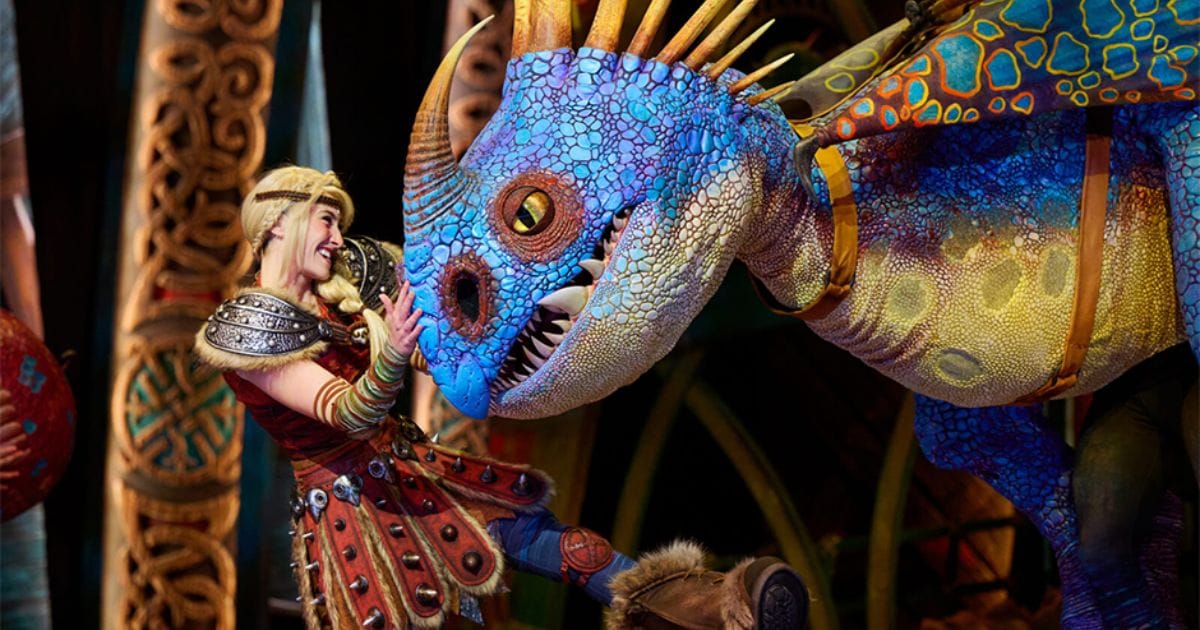 Live performers and a large dragon puppet on stage during The Untrainable Dragon show