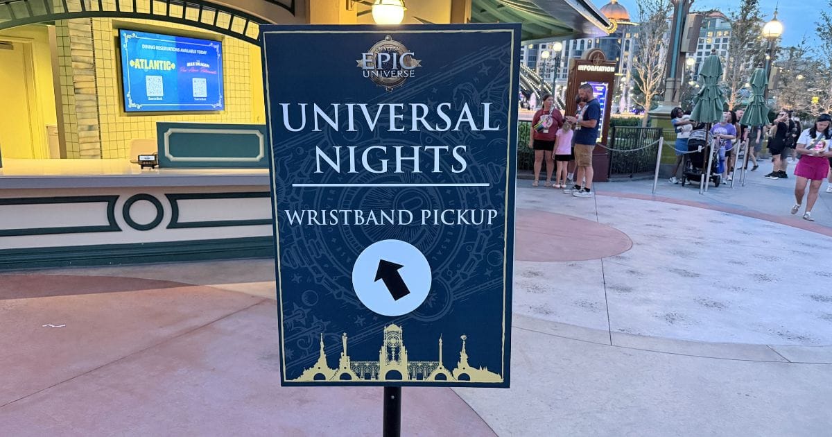 A directional sign for Universal Nights wristband pickup located inside Universal Epic Universe near the Atlantic restaurant.